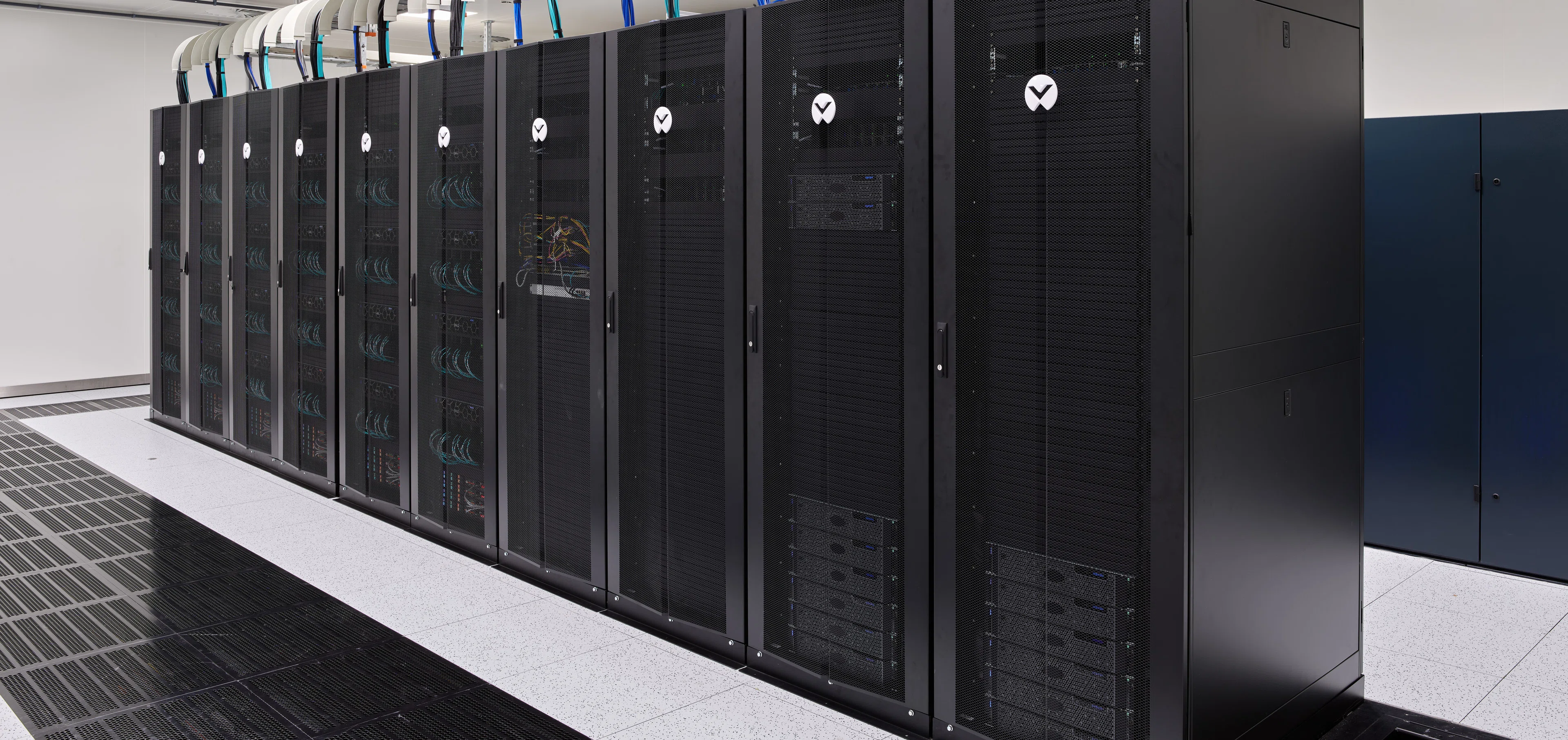 Eine Reihe von Supercomputer-Racks entlang des Kaltgangs in einer Halle des PHOENIQS-Rechenzentrums